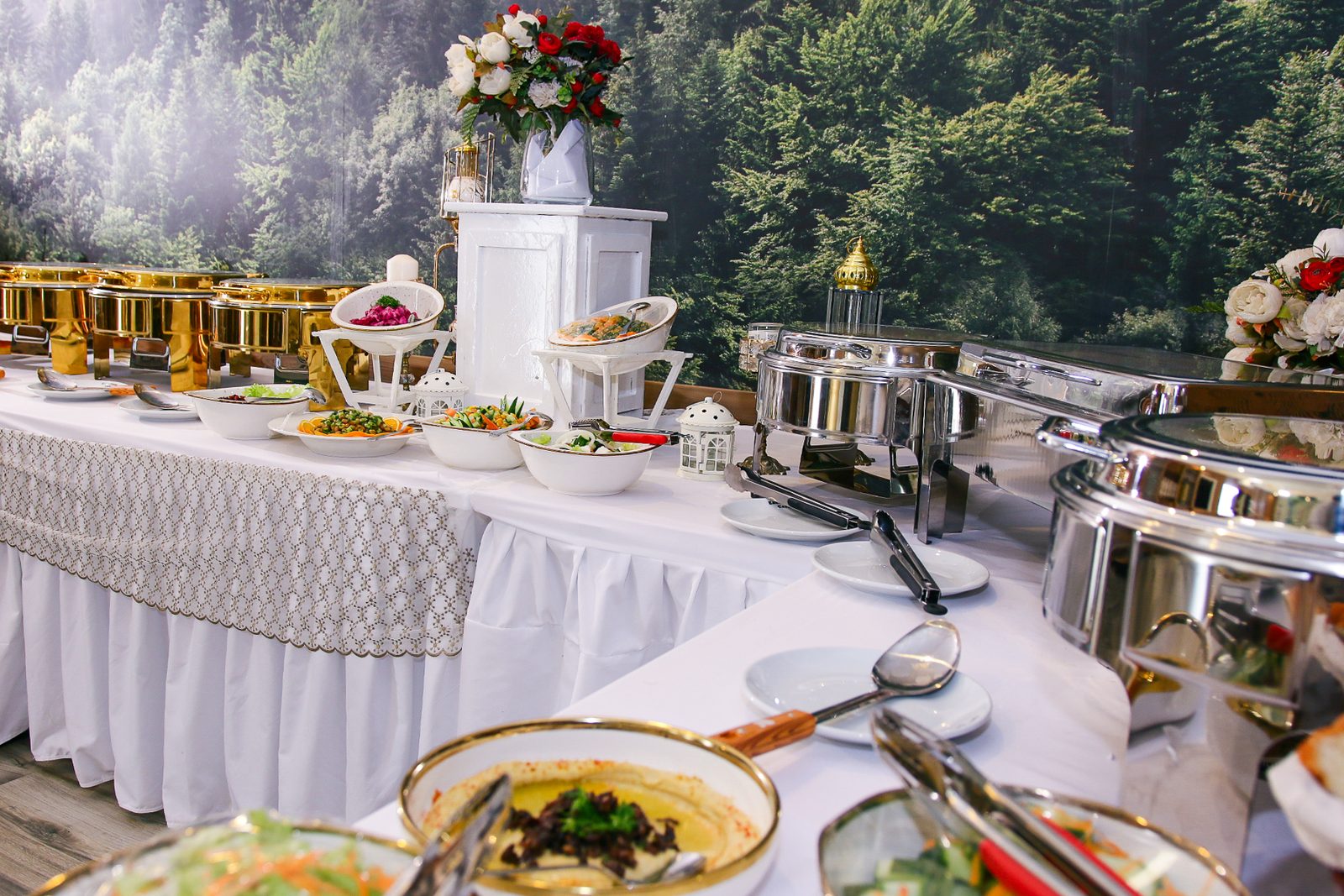 Excellence Café's lunch buffet — salads and mezze in gold-rimmed bowls beside gold and steel chafing dishes, with a floral centrepiece.
